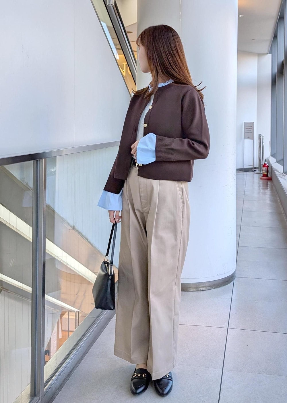 ブラック系のショルダーバッグ、ブラック系のローファー、ベージュ系のチノパンツを着用したレディースの冬コーディネートの3枚目の写真