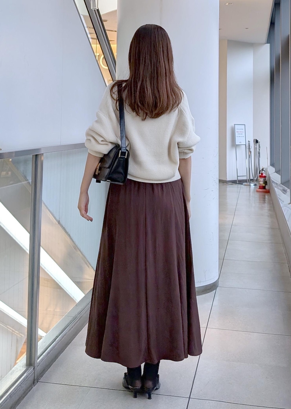ブラック系のパンプス、ブラック系のショルダーバッグ、ホワイト系のカーディガン/ボレロを着用したレディースの秋コーディネートの5枚目の写真