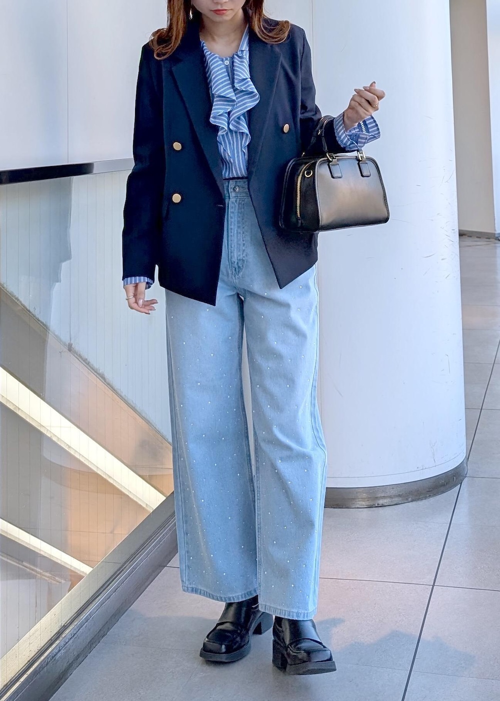 ブラック系のボストンバッグ、ブルー系のデニムパンツ、ブルー系のシャツ/ブラウスを着用したレディースの春コーディネートの2枚目の写真