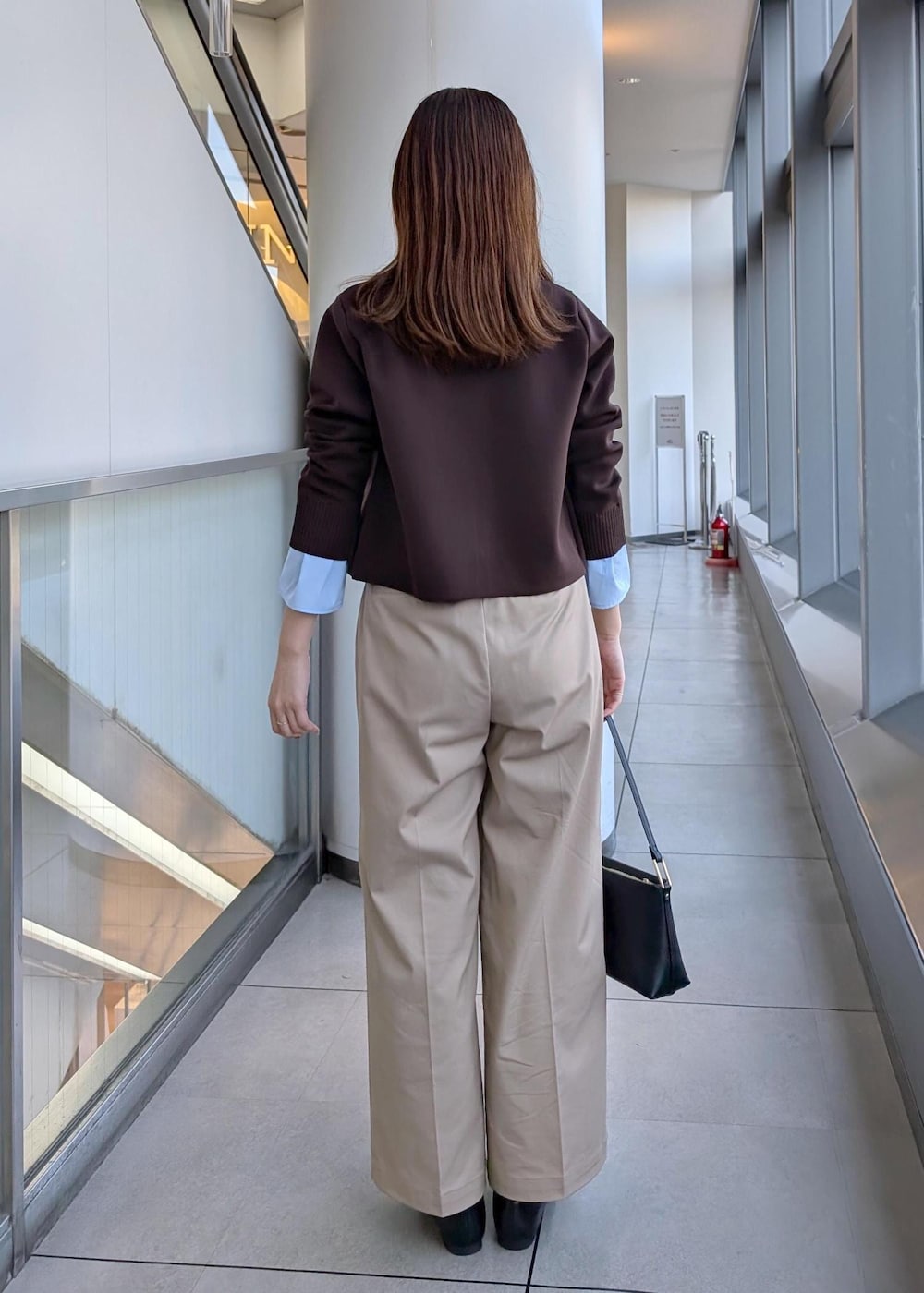 ブラック系のショルダーバッグ、ブラック系のローファー、ベージュ系のチノパンツを着用したレディースの冬コーディネートの7枚目の写真