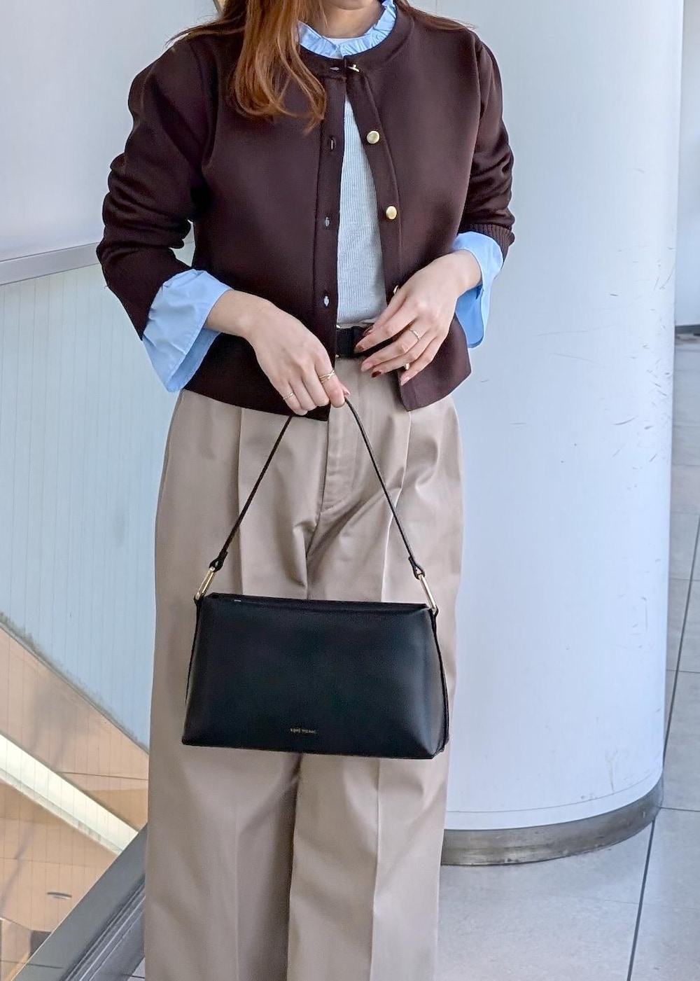 ブラック系のショルダーバッグ、ブラック系のローファー、ベージュ系のチノパンツを着用したレディースの冬コーディネートの4枚目の写真