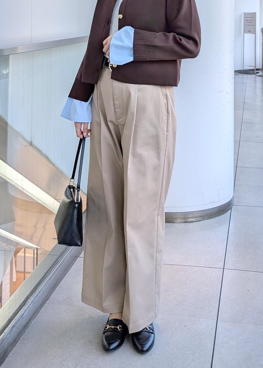 ブラック系のショルダーバッグ、ブラック系のローファー、ベージュ系のチノパンツを着用したレディースの冬コーディネートの5枚目の写真