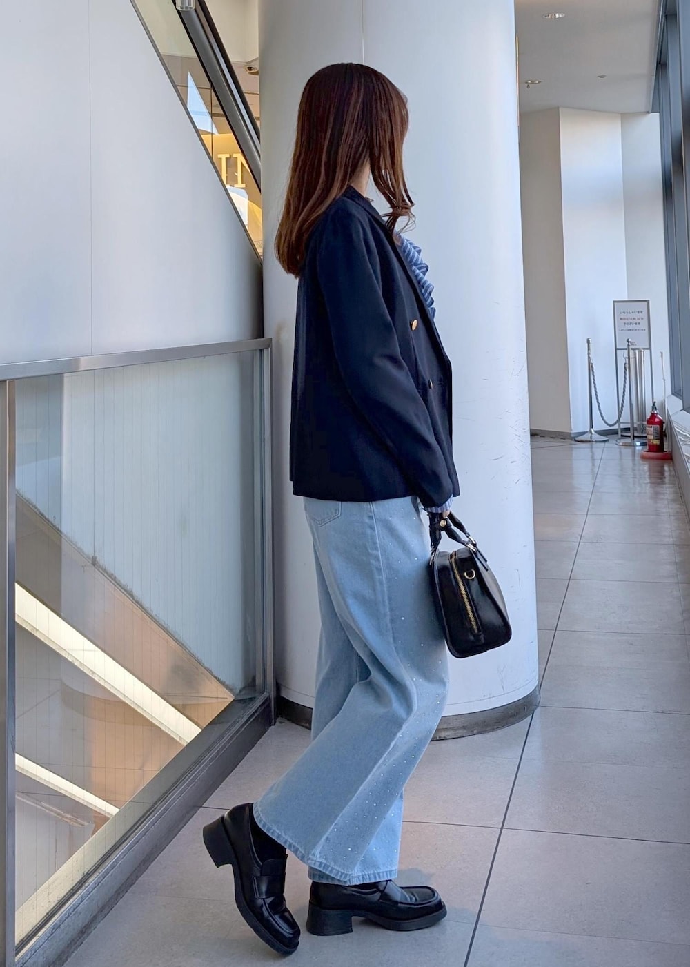 ブラック系のボストンバッグ、ブルー系のデニムパンツ、ブルー系のシャツ/ブラウスを着用したレディースの春コーディネートの4枚目の写真