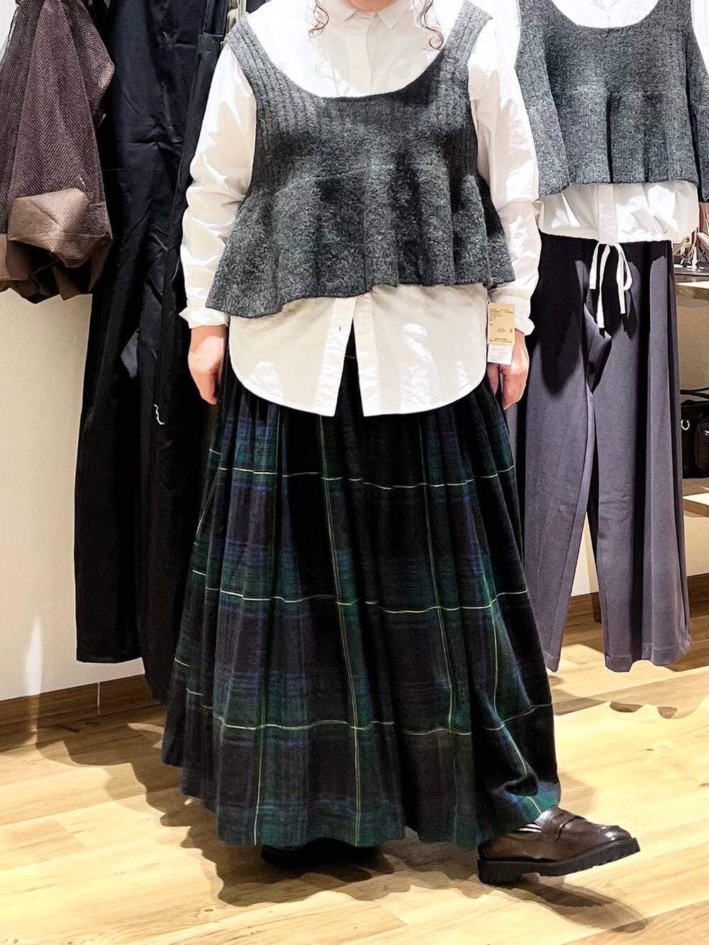 ブラウン系のローファー、ベージュ系のショルダーバッグ、グリーン系のスカートを着用したレディースの秋コーディネートの5枚目の写真