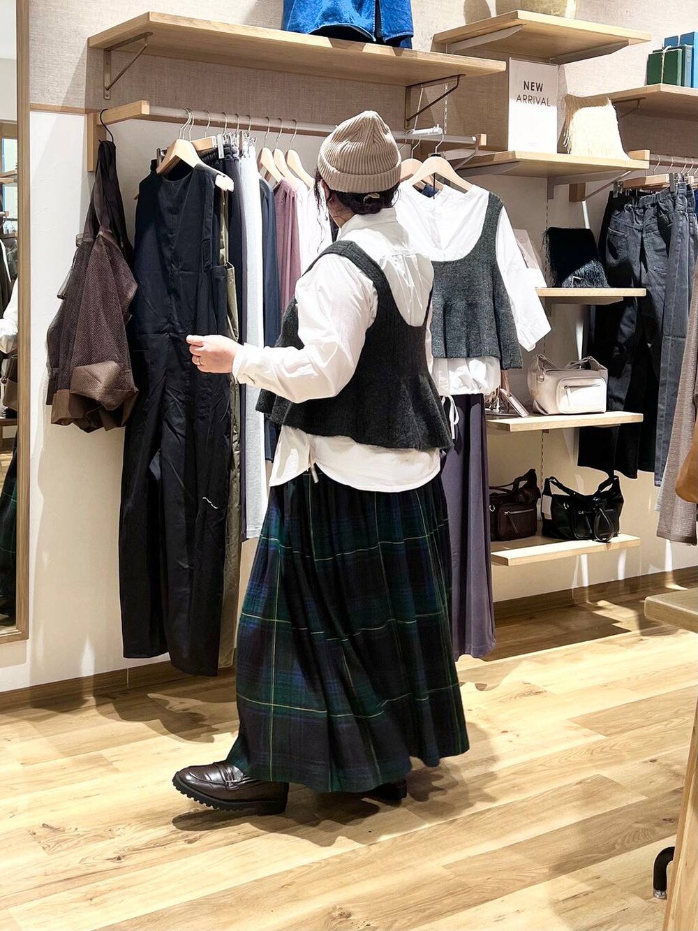 ブラウン系のローファー、ベージュ系のショルダーバッグ、グリーン系のスカートを着用したレディースの秋コーディネートの3枚目の写真