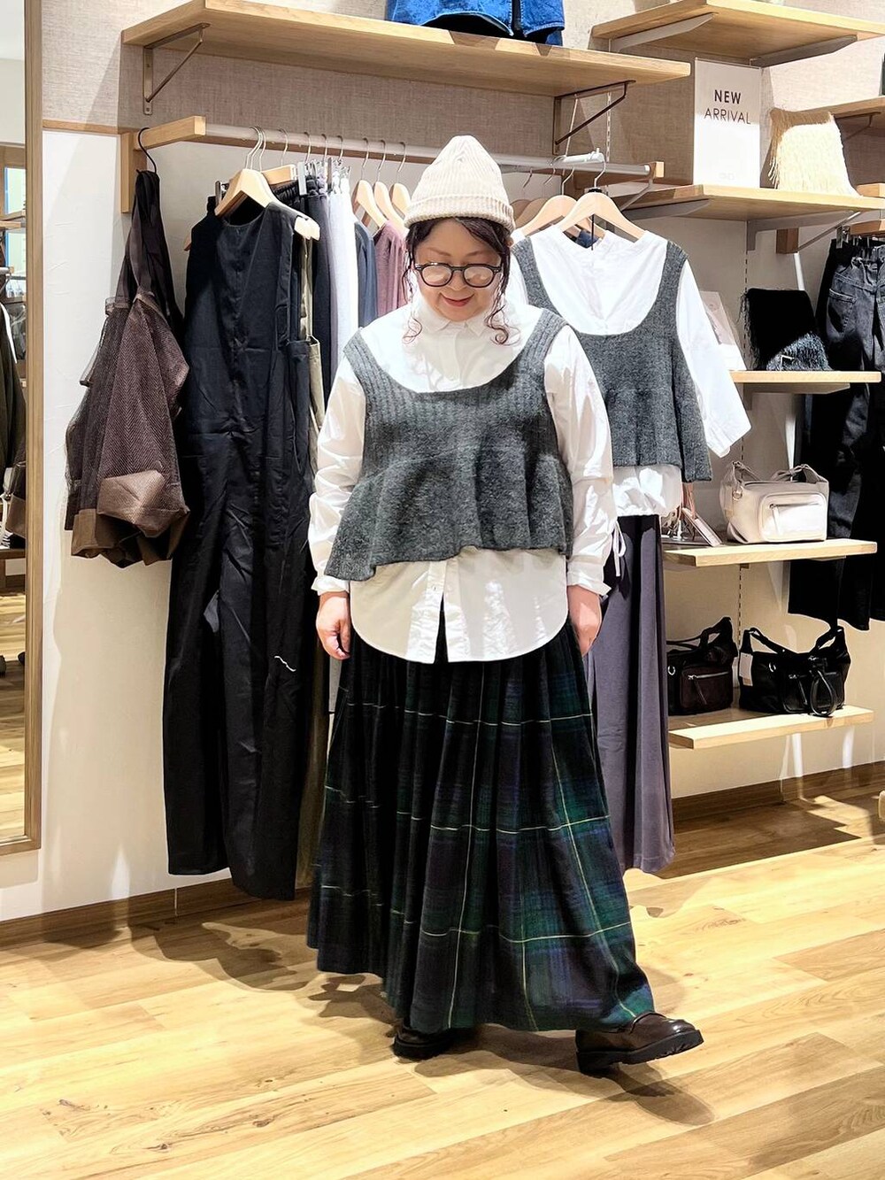 ブラウン系のローファー、ベージュ系のショルダーバッグ、グリーン系のスカートを着用したレディースの秋コーディネートの2枚目の写真