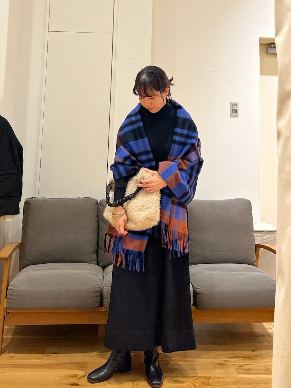 ブラック系のワンピース、ホワイト系のトートバッグ、ブラック系のブーツを着用したレディースの秋コーディネートの2枚目の写真