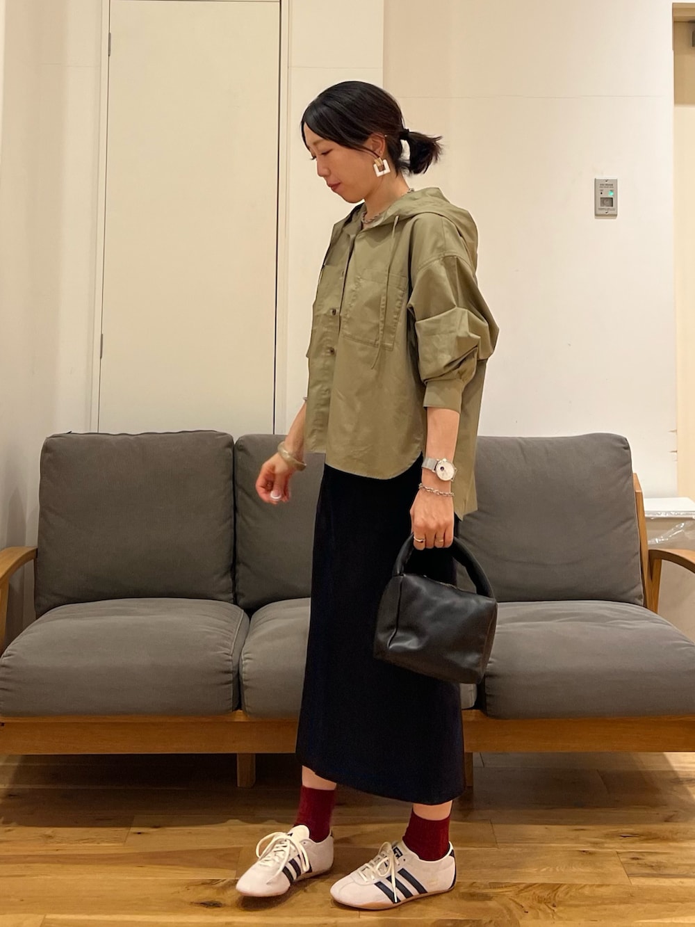 ブラック系のスカート、ブラック系のハンドバッグ、ホワイト系のスニーカーを着用したレディースの秋コーディネートの2枚目の写真