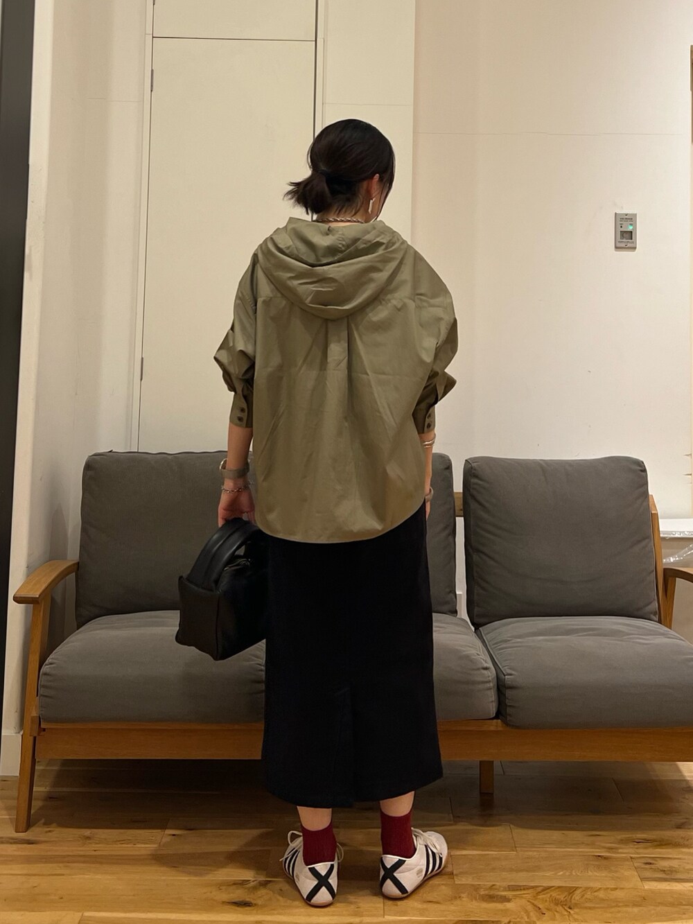 ブラック系のスカート、ブラック系のハンドバッグ、ホワイト系のスニーカーを着用したレディースの秋コーディネートの4枚目の写真