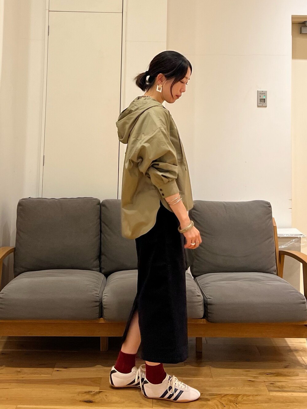 ブラック系のスカート、ブラック系のハンドバッグ、ホワイト系のスニーカーを着用したレディースの秋コーディネートの3枚目の写真