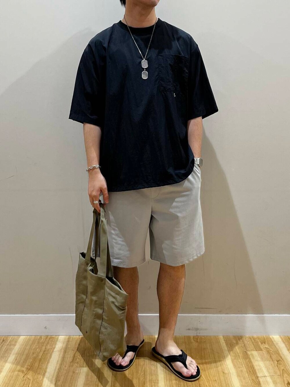 グリーン系のトートバッグ、グレー系のその他パンツ、ブラック系のTシャツ/カットソーを着用したメンズの夏コーディネートの3枚目の写真