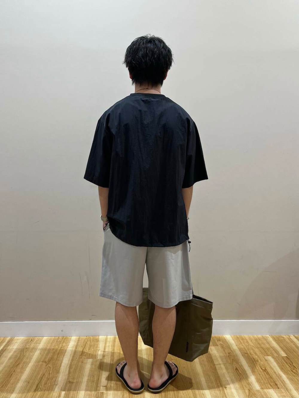 グリーン系のトートバッグ、グレー系のその他パンツ、ブラック系のTシャツ/カットソーを着用したメンズの夏コーディネートの2枚目の写真