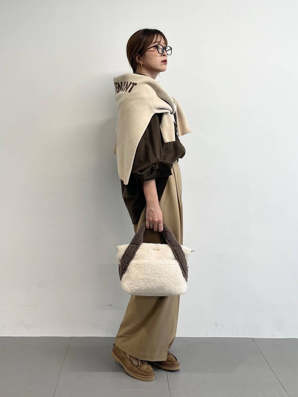 ホワイト系のトートバッグ、ベージュ系のローファー、イエロー系のスラックスを着用したレディースの秋コーディネートの2枚目の写真