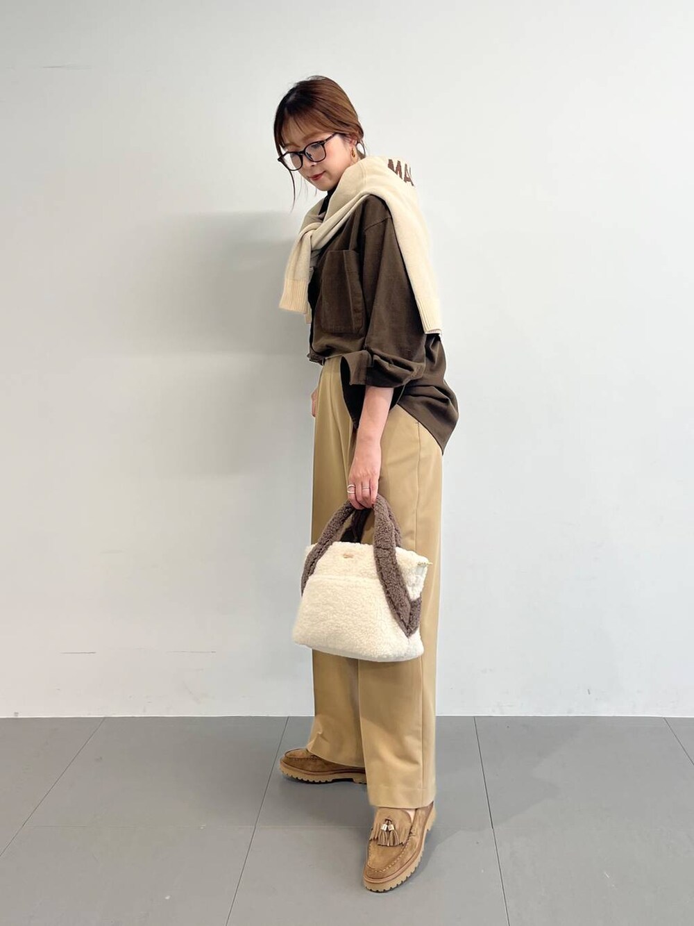 ホワイト系のトートバッグ、ベージュ系のローファー、イエロー系のスラックスを着用したレディースの秋コーディネートの4枚目の写真