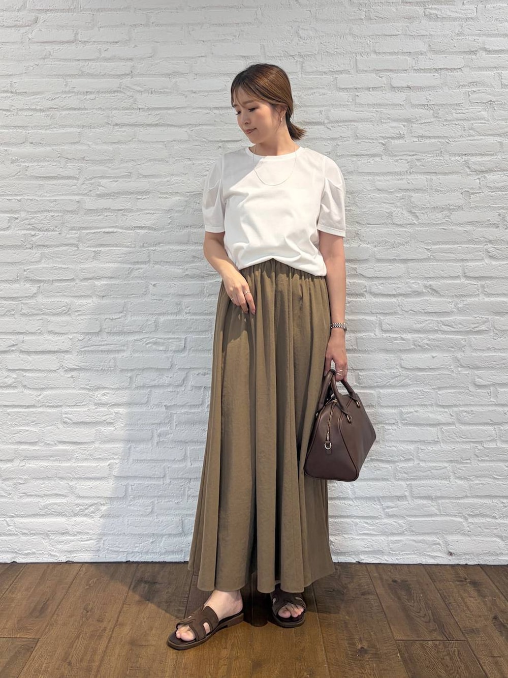 ホワイト系のTシャツ/カットソー、ブラウン系のボストンバッグ、ベージュ系のスカートを着用したレディースの夏コーディネートの2枚目の写真