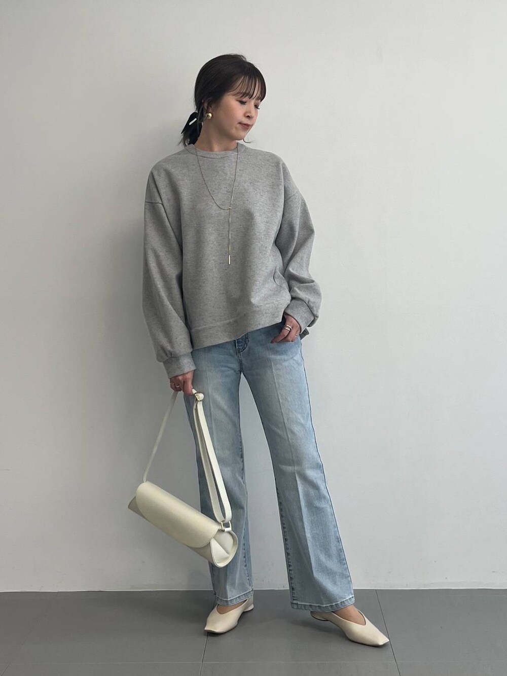 ホワイト系のショルダーバッグ、グレー系のスウェットを着用したレディースの冬コーディネートの2枚目の写真