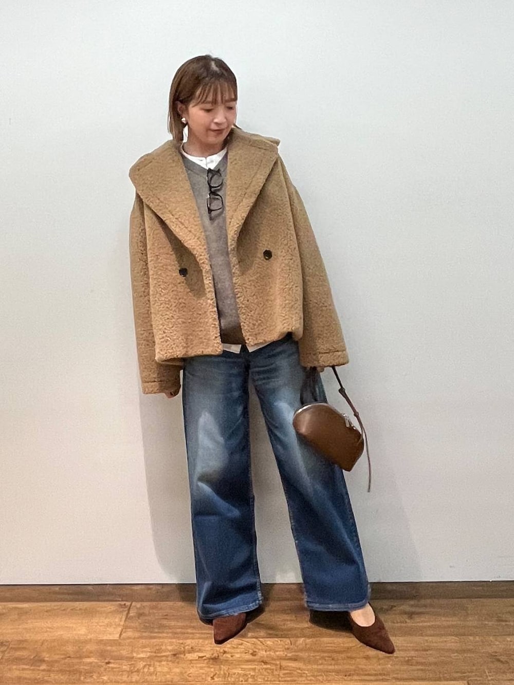 イエロー系のピーコート、ブラウン系のショルダーバッグ、ホワイト系のシャツ/ブラウスを着用したレディースの秋コーディネートの2枚目の写真