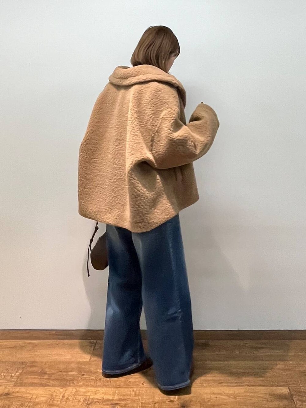 イエロー系のピーコート、ブラウン系のショルダーバッグ、ホワイト系のシャツ/ブラウスを着用したレディースの秋コーディネートの3枚目の写真