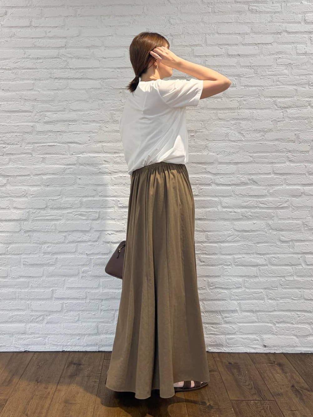 ホワイト系のTシャツ/カットソー、ブラウン系のボストンバッグ、ベージュ系のスカートを着用したレディースの夏コーディネートの5枚目の写真
