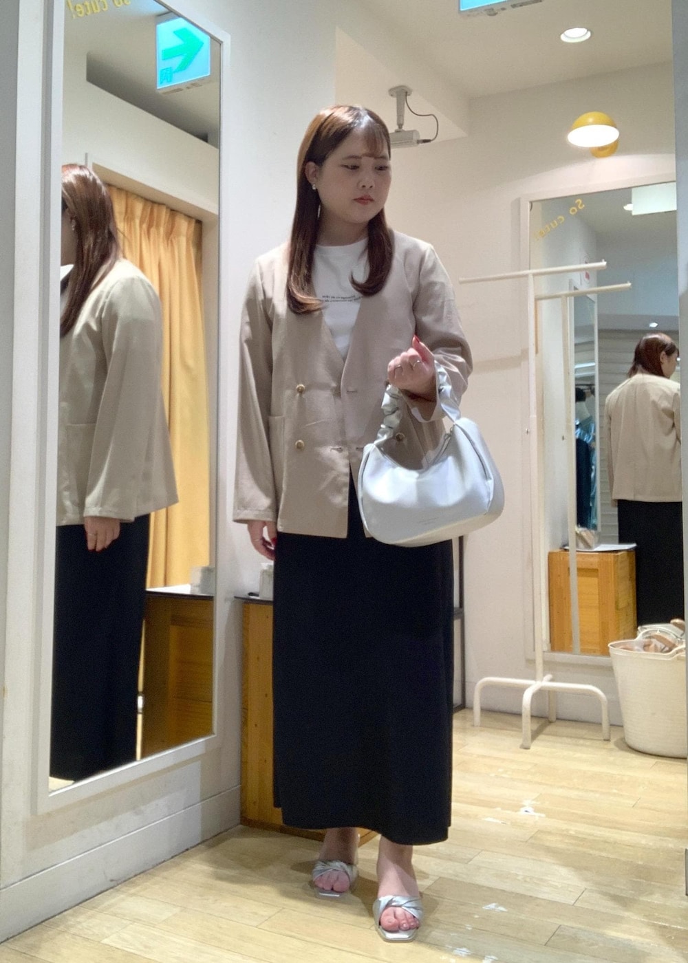 シルバー系のハンドバッグ、シルバー系のサンダル、ベージュ系のテーラードジャケットを着用したレディースの夏コーディネートの2枚目の写真