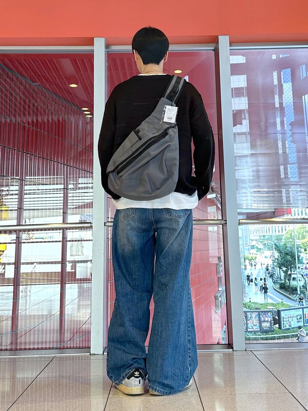 ブルー系のデニムパンツ、グレー系のバックパック/リュック、ブラック系のニット/セーターを着用したメンズの秋コーディネートの3枚目の写真