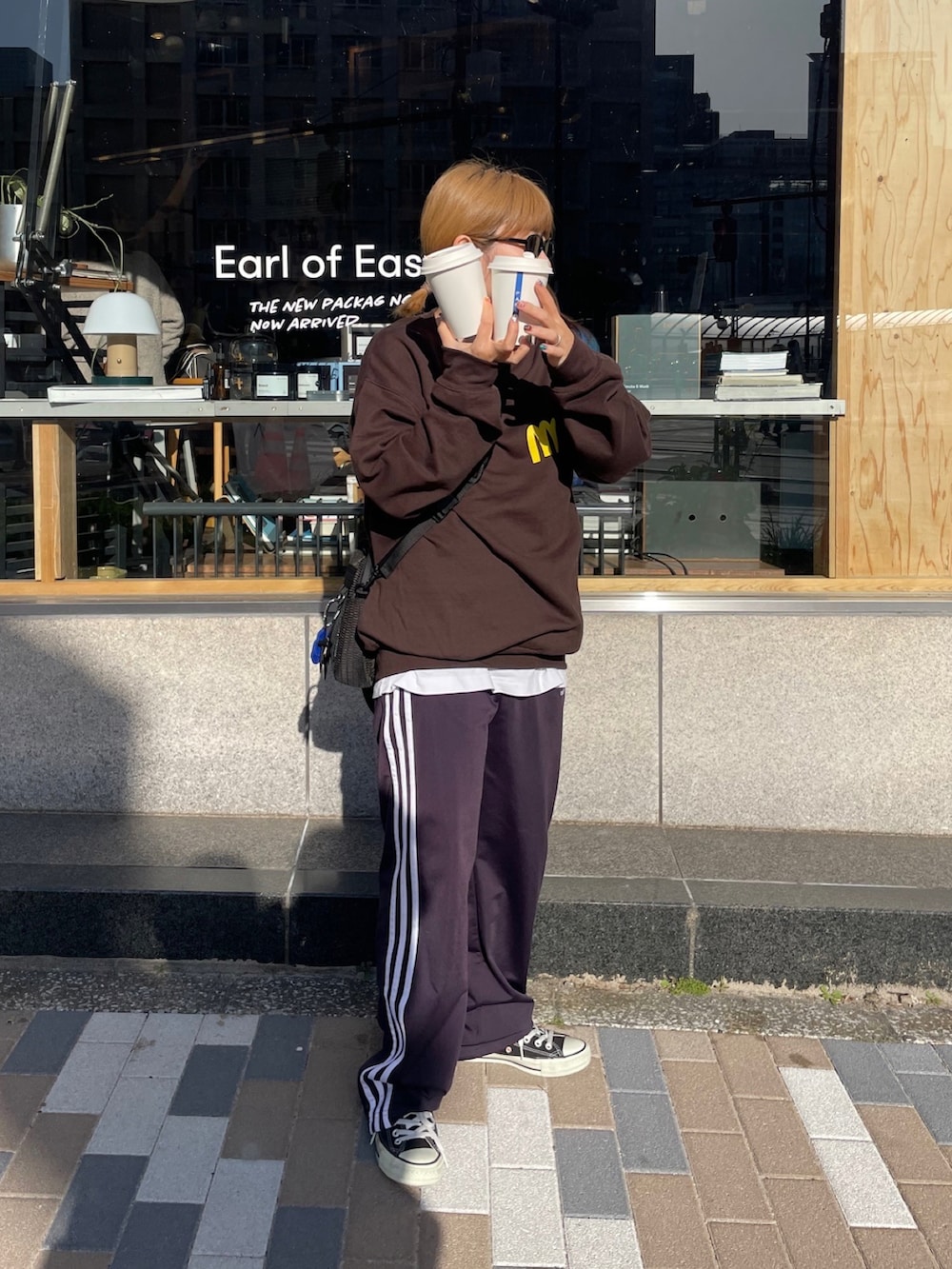 ブルー系のスウェットパンツ、ブラック系のスニーカー、ブラウン系のスウェットを着用したレディースの春コーディネートの2枚目の写真