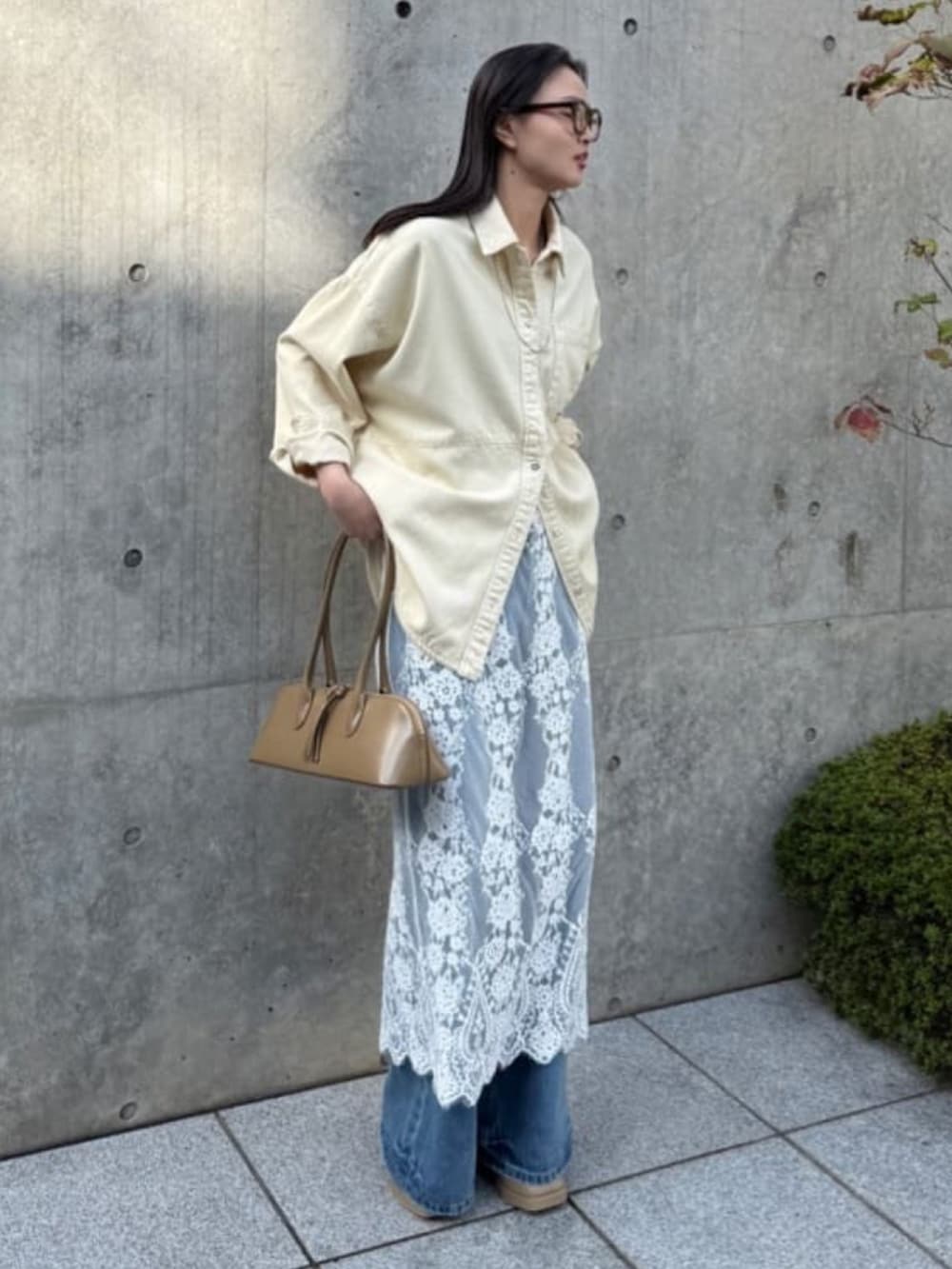 イエロー系のトップス、ホワイト系のスカート、ブルー系のデニムパンツを着用したレディースの冬コーディネートの2枚目の写真