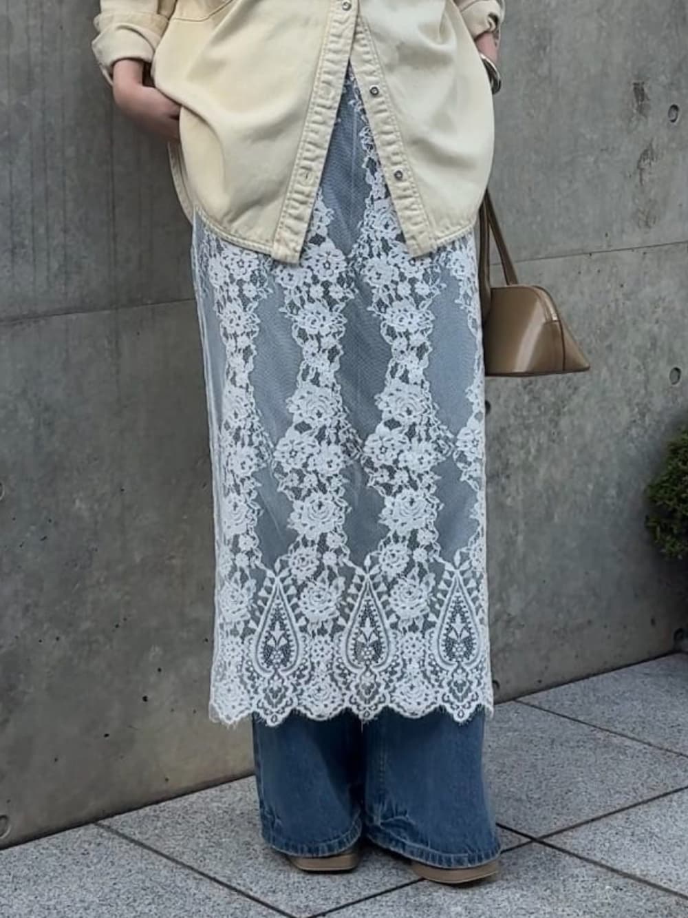 イエロー系のトップス、ホワイト系のスカート、ブルー系のデニムパンツを着用したレディースの冬コーディネートの4枚目の写真