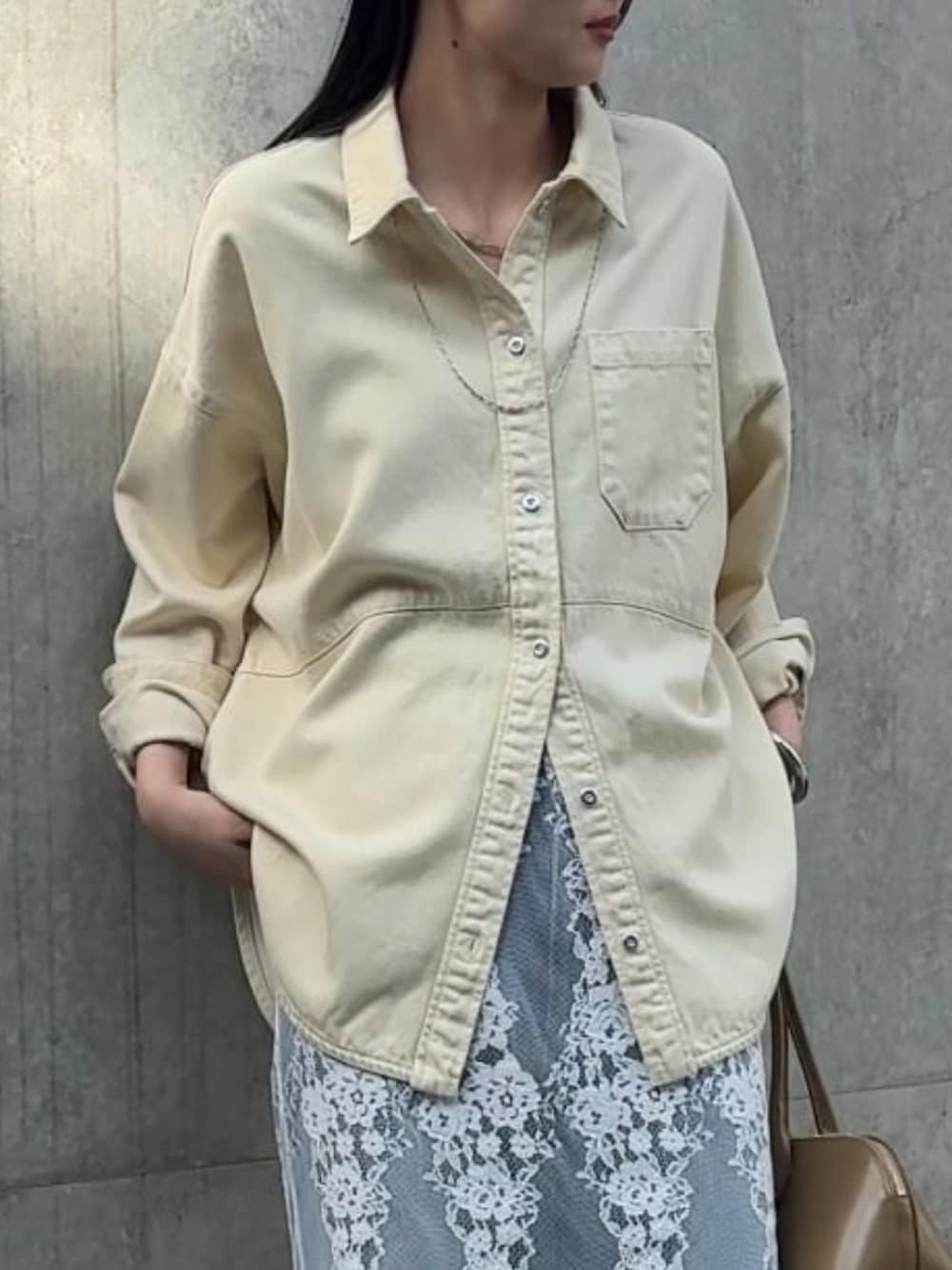 イエロー系のトップス、ホワイト系のスカート、ブルー系のデニムパンツを着用したレディースの冬コーディネートの3枚目の写真