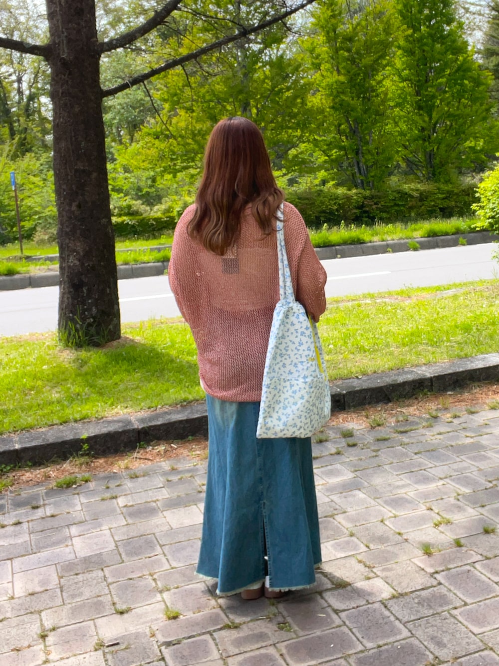 ブルー系のスカート、オレンジ系のニット/セーター、ブルー系のトートバッグを着用したレディースの春コーディネートの5枚目の写真