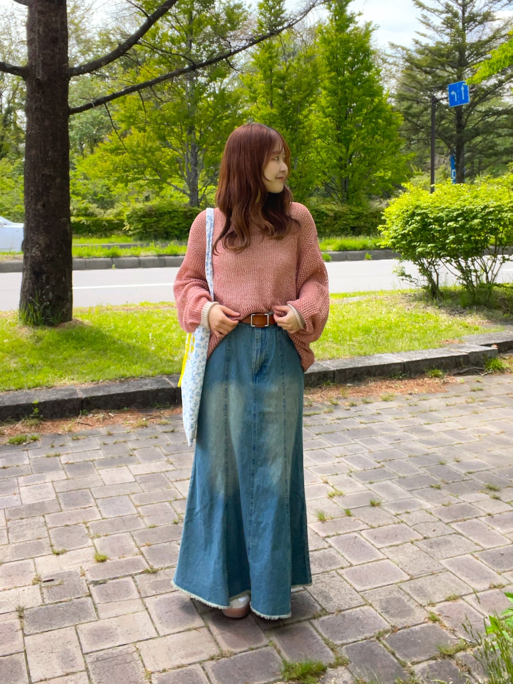 ブルー系のスカート、オレンジ系のニット/セーター、ブルー系のトートバッグを着用したレディースの春コーディネートの2枚目の写真