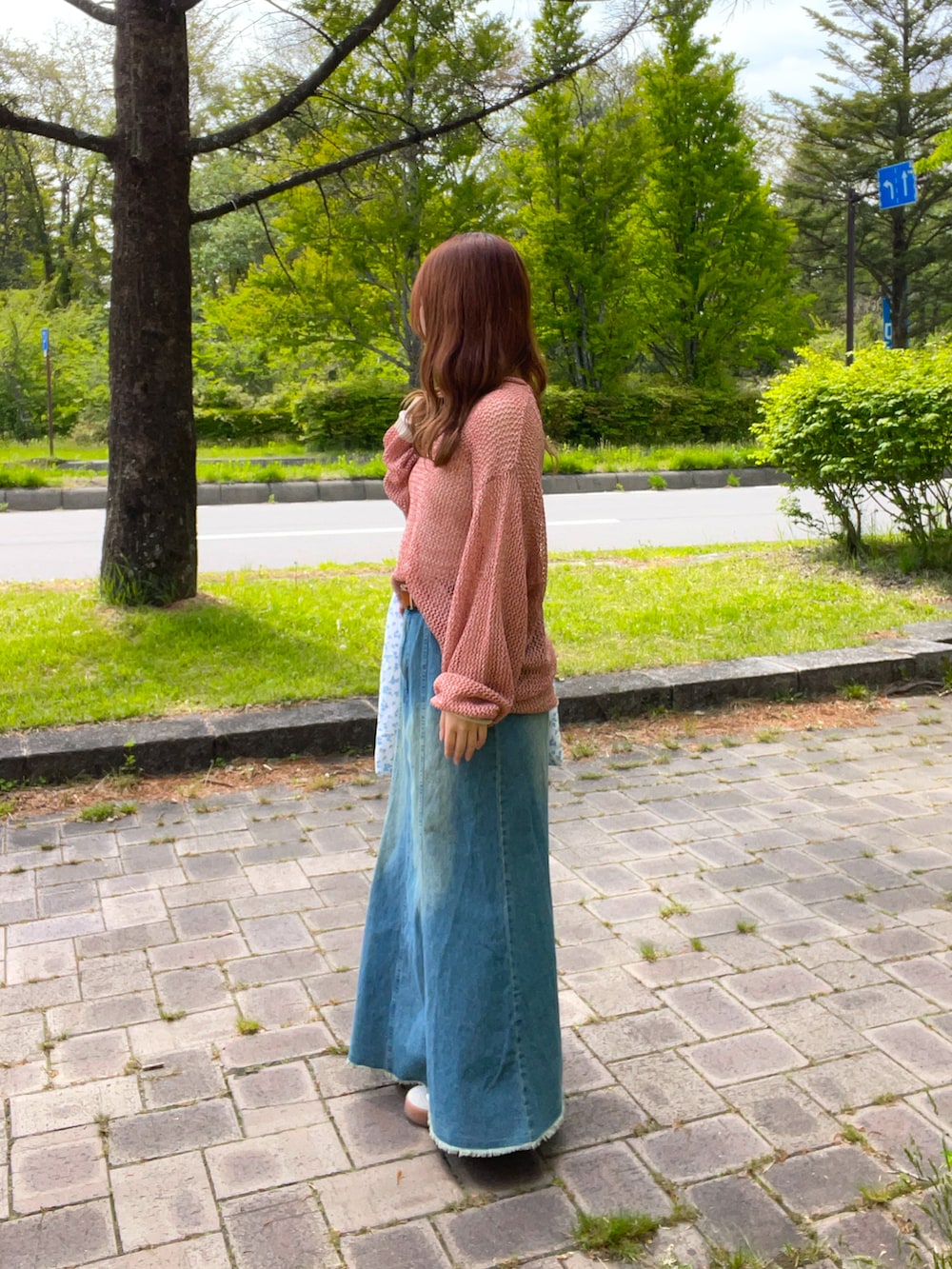 ブルー系のスカート、オレンジ系のニット/セーター、ブルー系のトートバッグを着用したレディースの春コーディネートの4枚目の写真