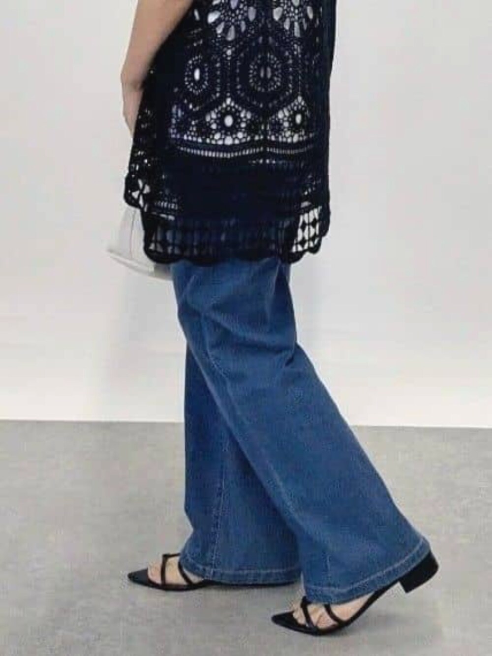 ブルー系のデニムパンツ、ブラック系のサンダル、ブラック系のベストを着用したレディースの夏コーディネートの2枚目の写真