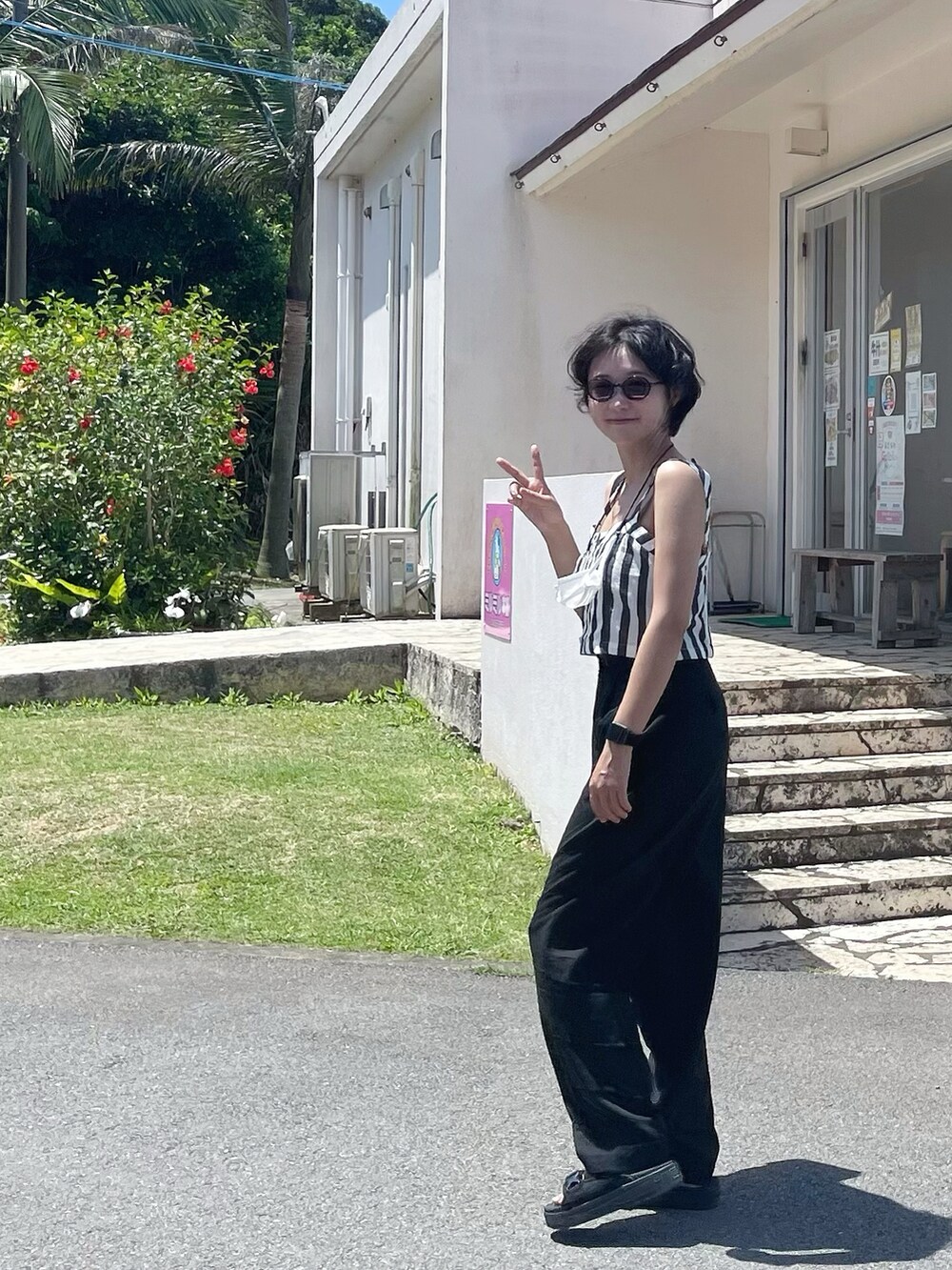 ブラック系のスラックス、ブラック系のサンダルを着用したレディースの春コーディネートの2枚目の写真