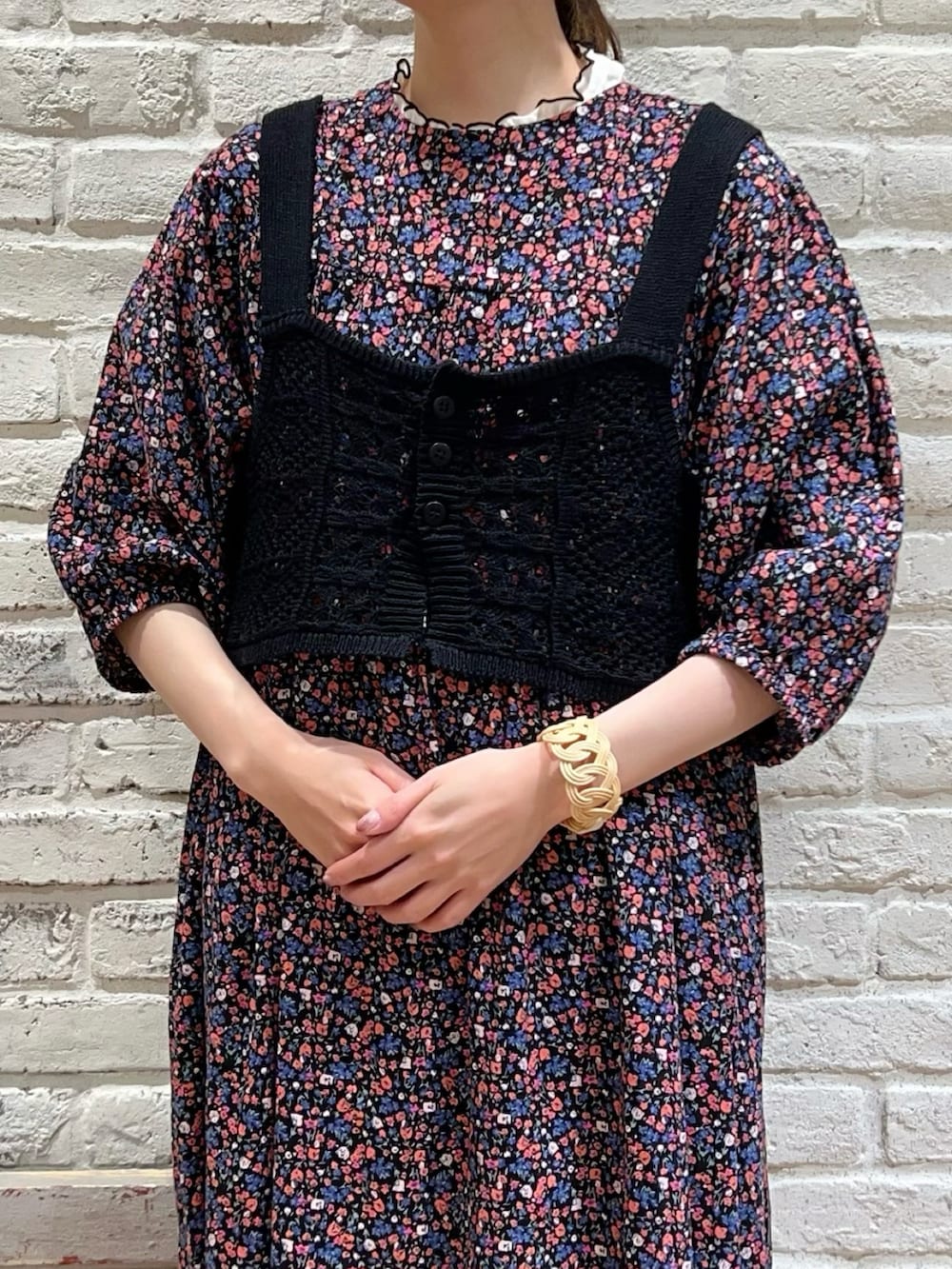 ブラック系のベスト、ピンク系のワンピース、ブラック系のハンドバッグを着用したレディースの夏コーディネートの2枚目の写真