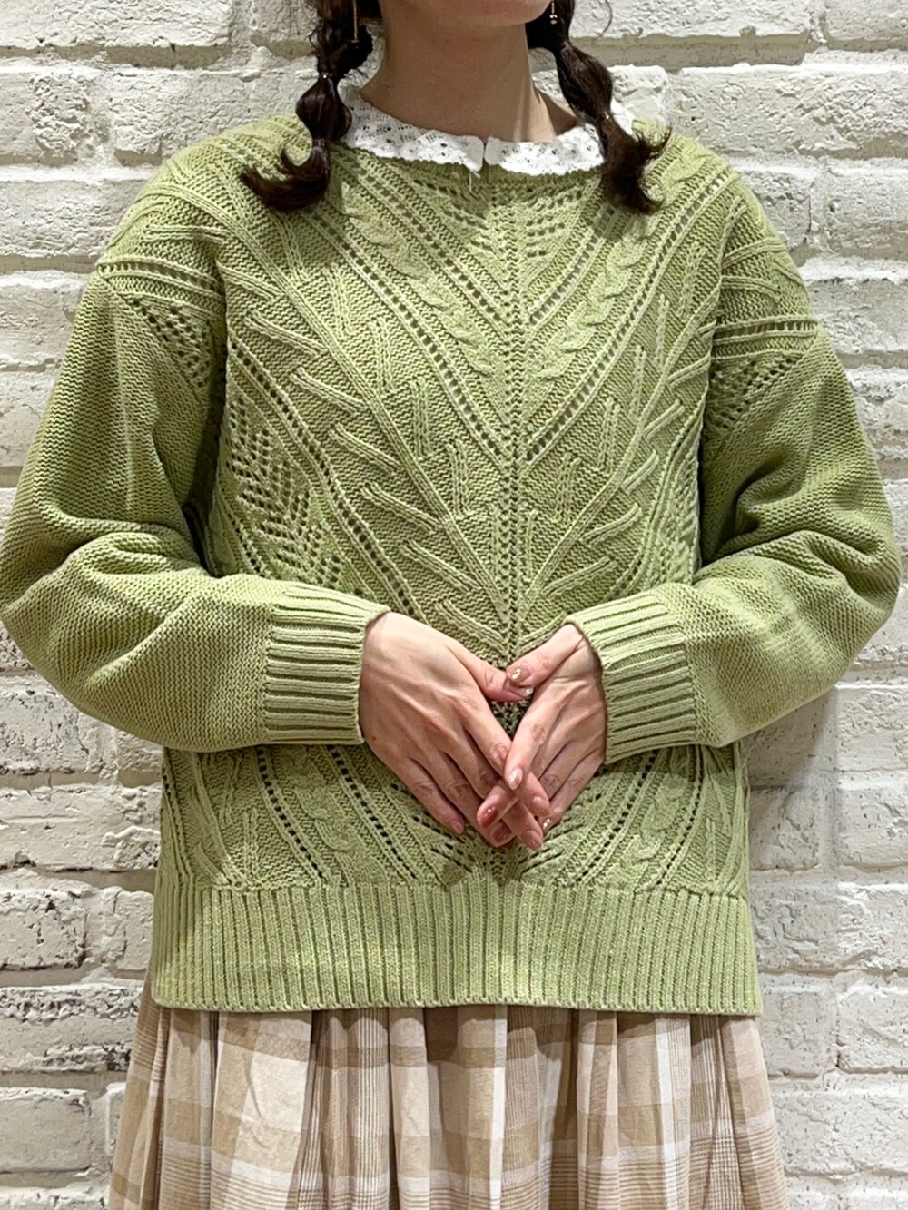 グリーン系のニット/セーター、ベージュ系のスカート、ブラウン系のブーツを着用したレディースの冬コーディネートの2枚目の写真