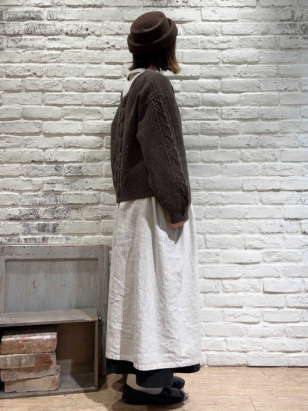 ブラウン系のカーディガン/ボレロ、ベージュ系のワンピース、ブラック系のスカートを着用したレディースの秋コーディネートの4枚目の写真