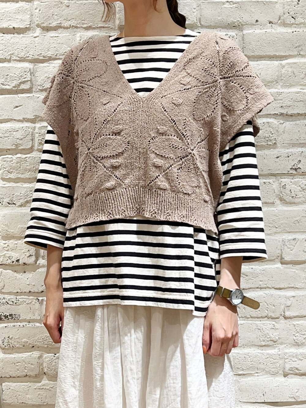 ホワイト系のTシャツ/カットソー、ベージュ系のベスト、ブラック系のハットを着用したレディースの秋コーディネートの2枚目の写真