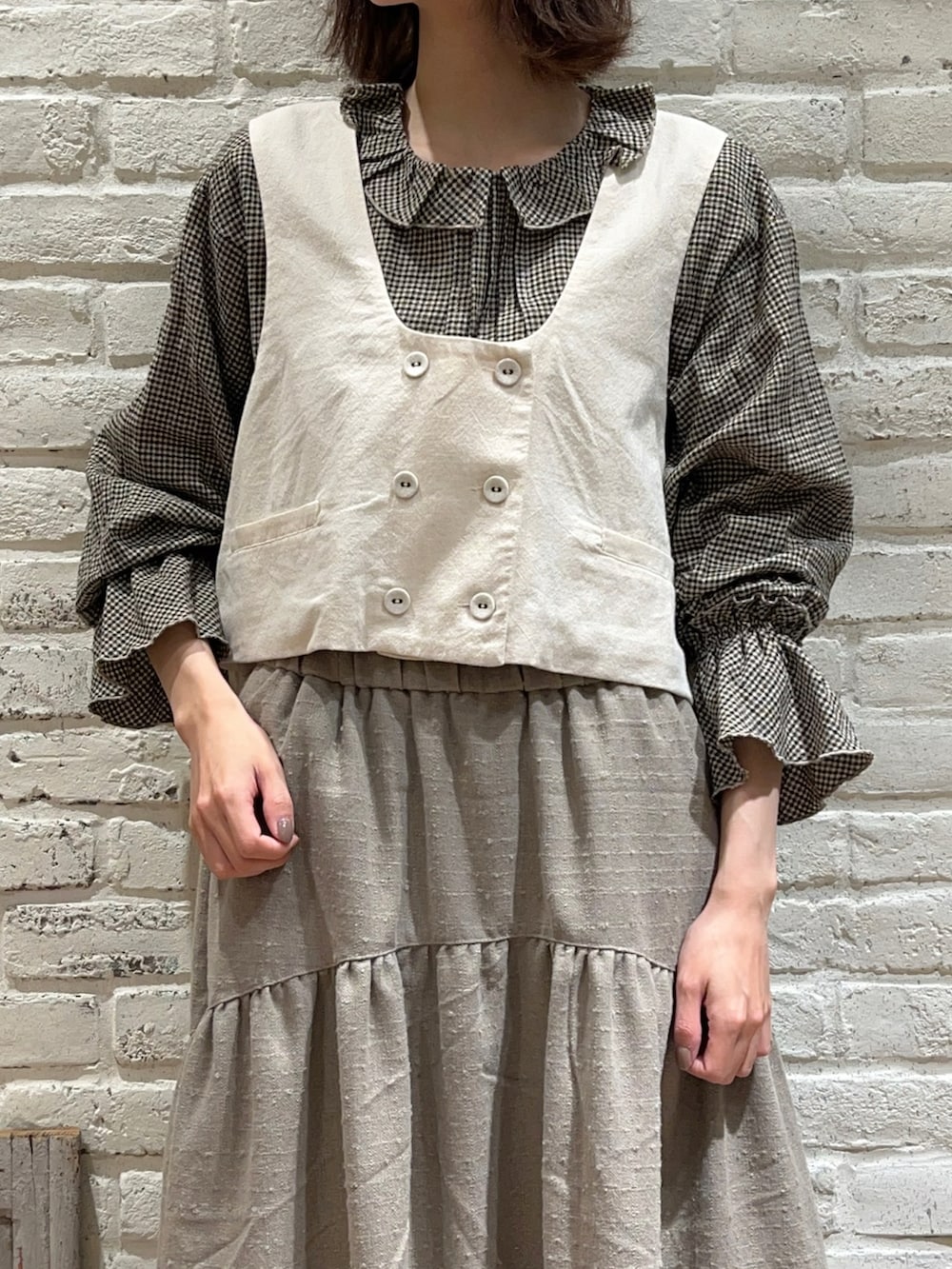 ブラウン系のシャツ/ブラウス、ホワイト系のベスト、ブラウン系のスカートを着用したレディースの冬コーディネートの2枚目の写真