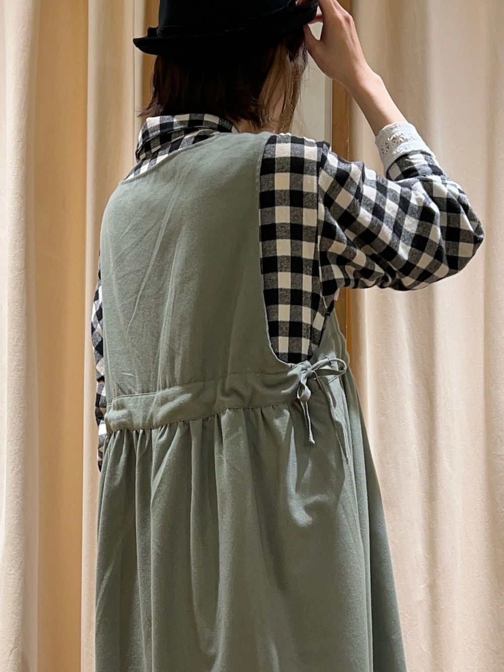 ホワイト系のTシャツ/カットソー、グリーン系のジャンパースカート、ブラック系のシャツワンピースを着用したレディースの冬コーディネートの5枚目の写真