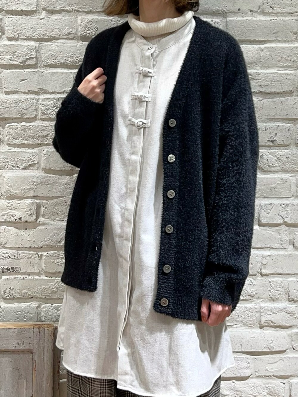 ホワイト系のニット/セーター、グレー系のチュニック、ブラック系のカーディガン/ボレロを着用したレディースの冬コーディネートの2枚目の写真