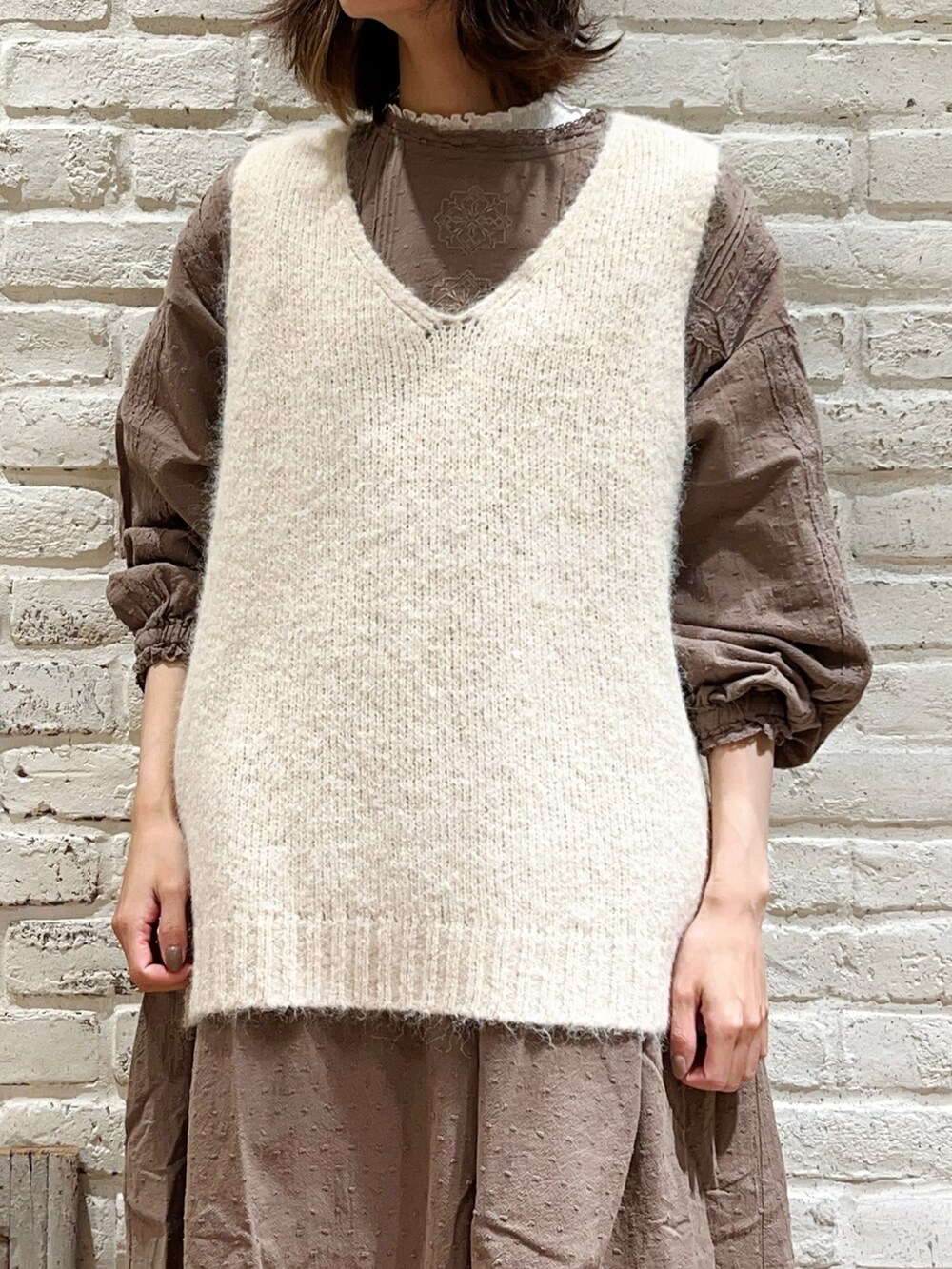 ホワイト系のTシャツ/カットソー、ホワイト系のベスト、ブラウン系のワンピースを着用したレディースの冬コーディネートの2枚目の写真