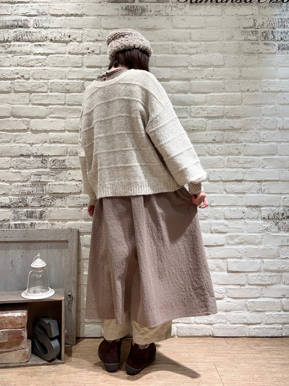 ホワイト系のカーディガン/ボレロ、ブラウン系のワンピース、ベージュ系のカーゴパンツを着用したレディースの冬コーディネートの4枚目の写真