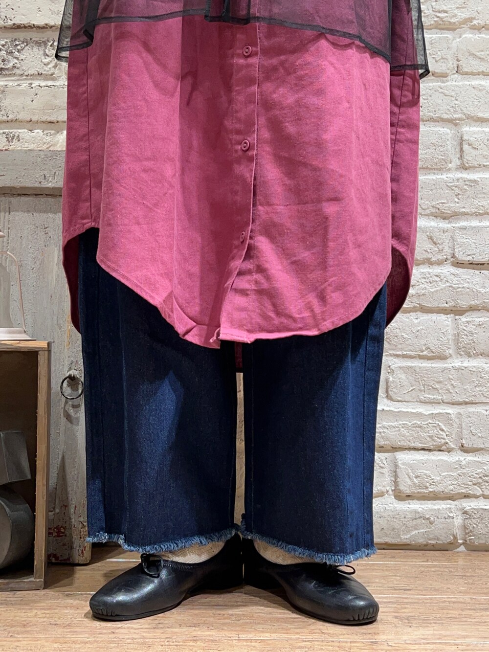 パープル系のワンピース、ブラック系のベスト、ブルー系のデニムパンツを着用したレディースの秋コーディネートの5枚目の写真