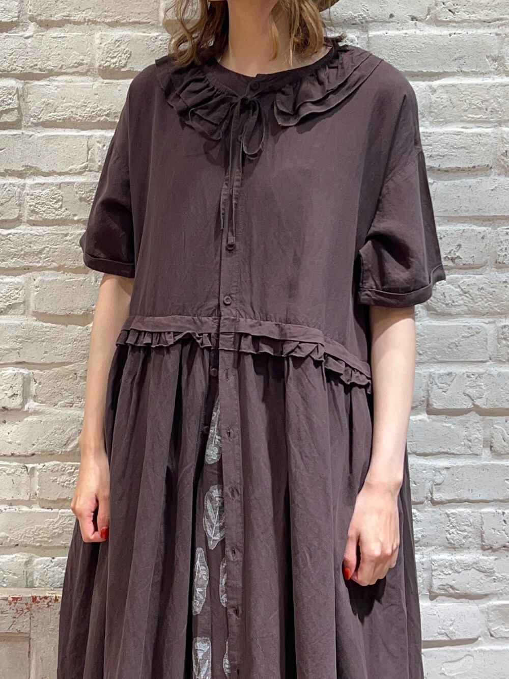 グレー系のワンピース、ブラウン系のスカート、ブラック系のサンダルを着用したレディースの春コーディネートの2枚目の写真