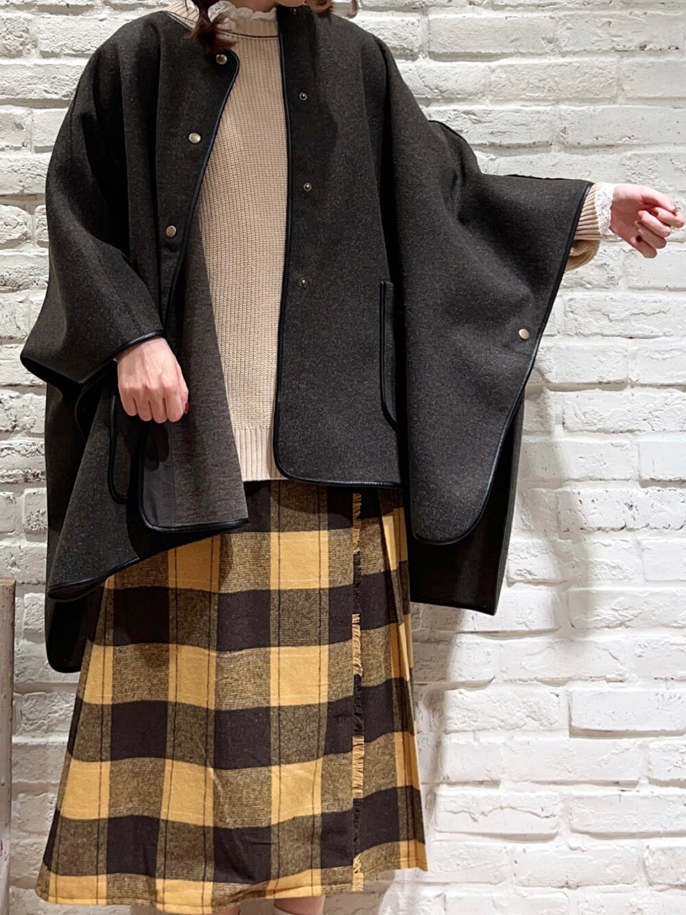 ホワイト系のTシャツ/カットソー、ブラウン系のポンチョ、ホワイト系のニット/セーターを着用したレディースの秋コーディネートの2枚目の写真