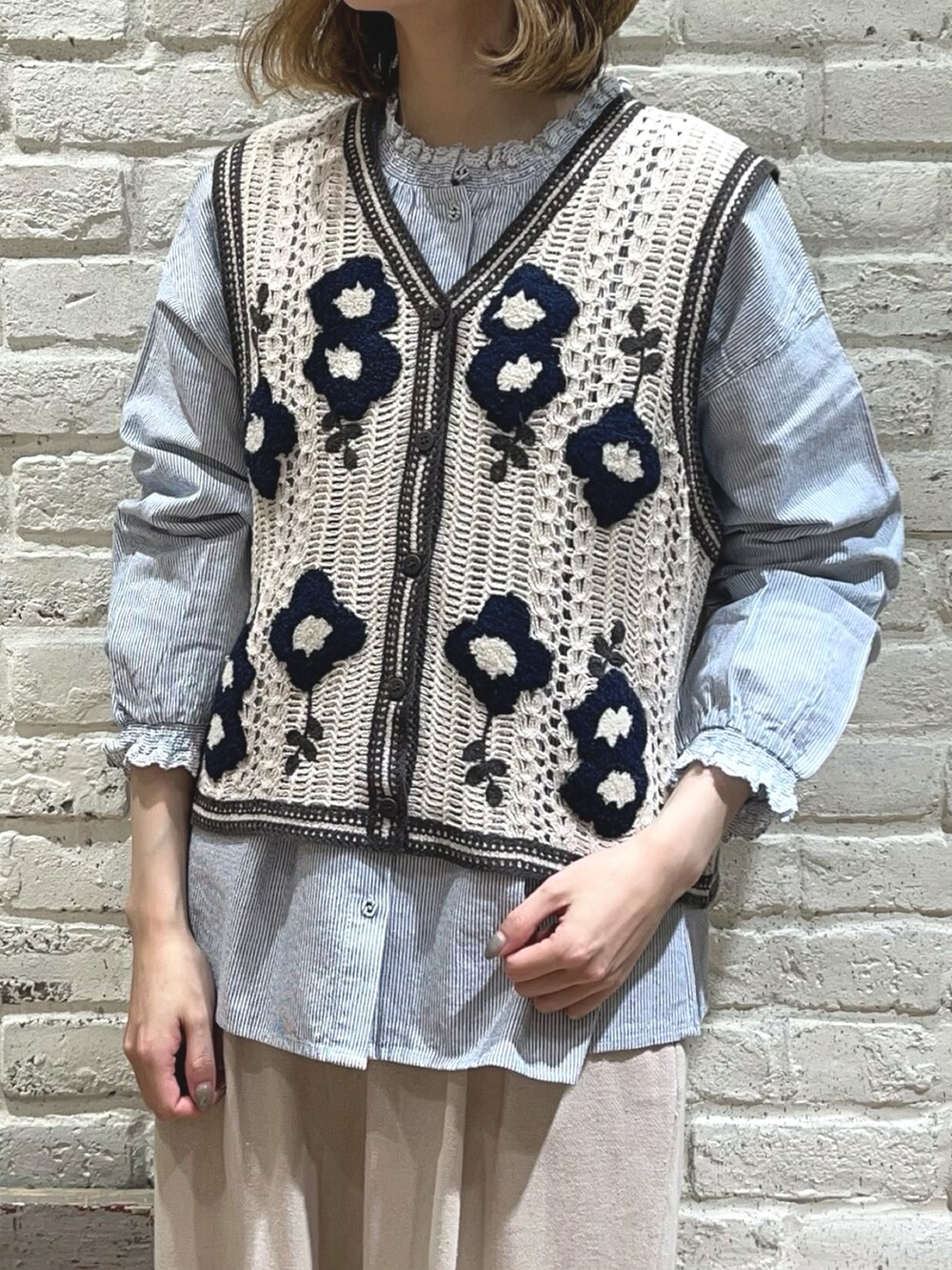 ブルー系のシャツ/ブラウス、ホワイト系のベスト、ブラック系のハンドバッグを着用したレディースの春コーディネートの2枚目の写真