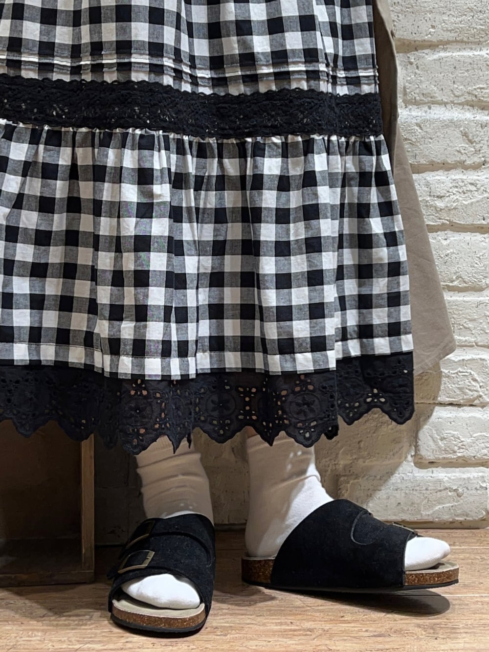 ブラック系のチュニック、ベージュ系のワンピース、ブラック系のハンドバッグを着用したレディースの夏コーディネートの5枚目の写真