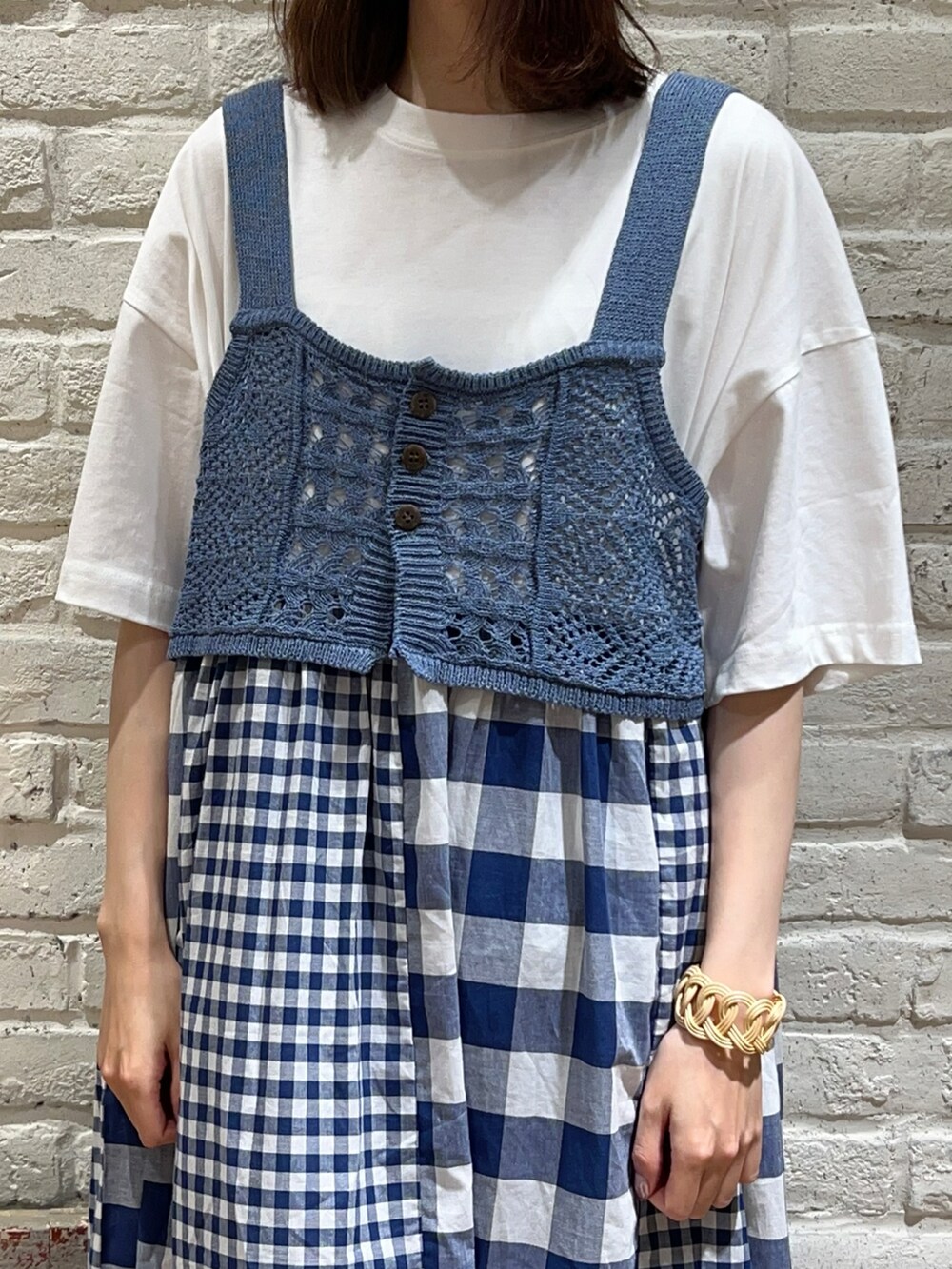 ブルー系のベスト、ホワイト系のワンピース、ホワイト系のハンドバッグを着用したレディースの秋コーディネートの2枚目の写真