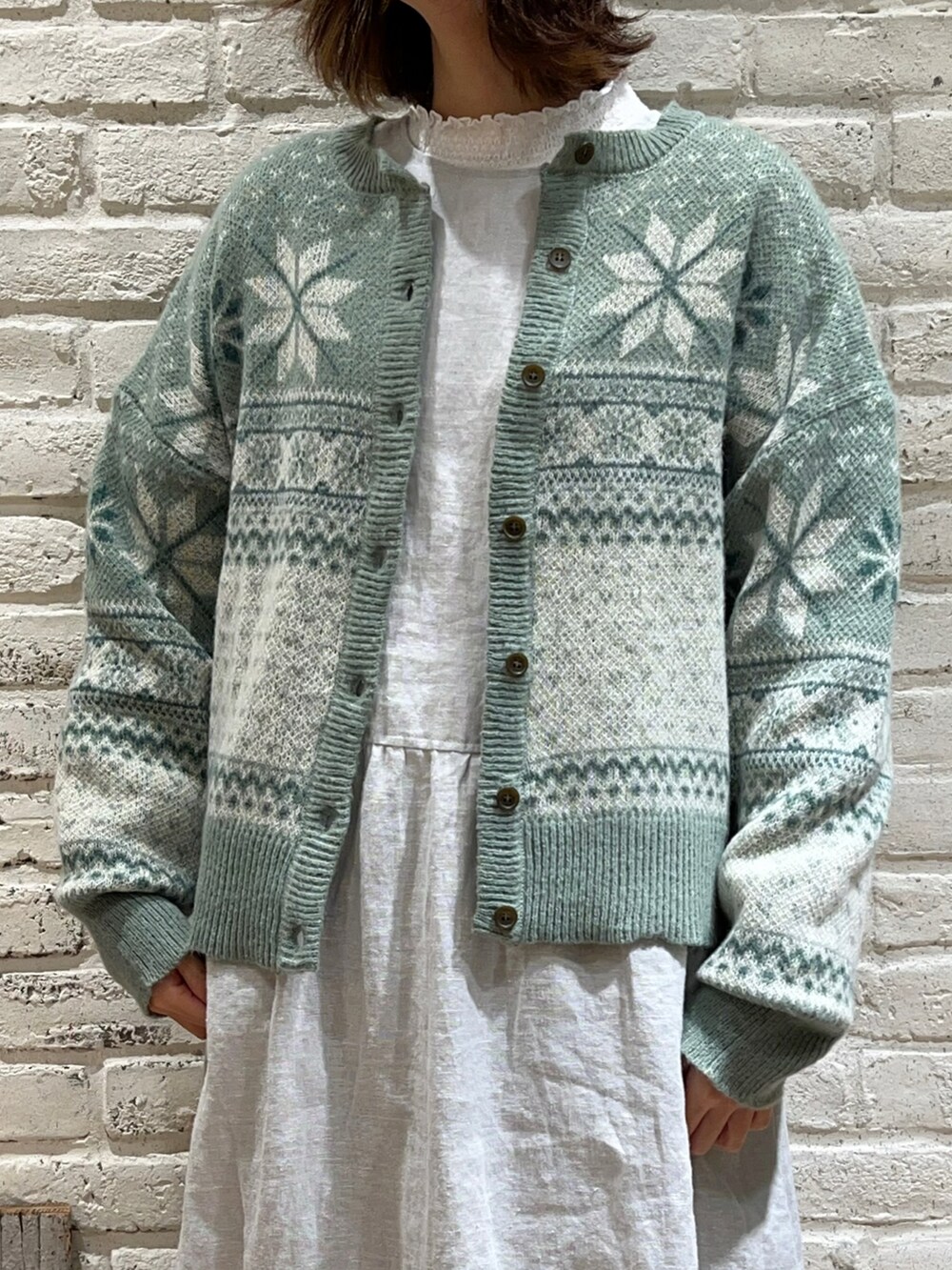 ホワイト系のTシャツ/カットソー、グリーン系のカーディガン/ボレロ、グリーン系のワンピースを着用したレディースの冬コーディネートの2枚目の写真